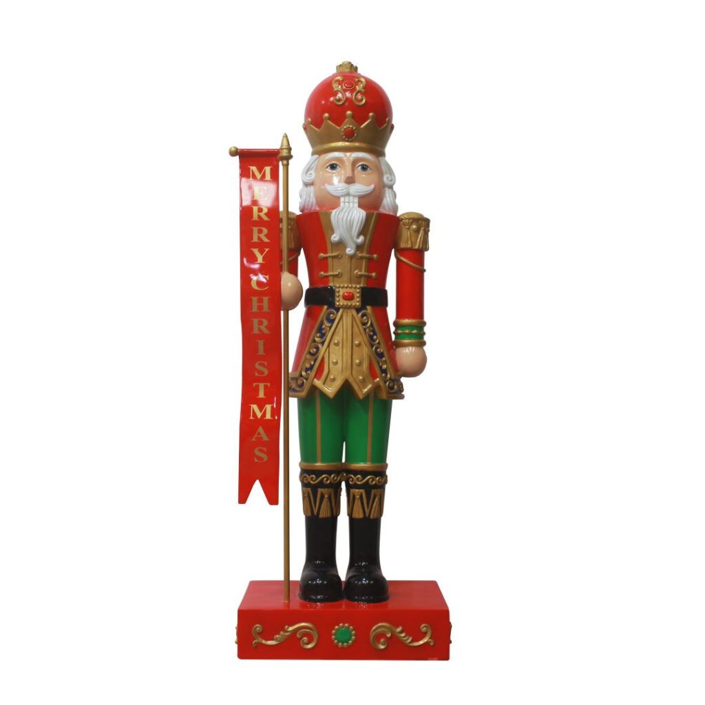 A traditional style nutcracker figurine holding a banner that says "Merry Christmas".