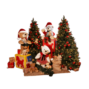 A group of three teddy bears on large toy blocks next to decorated Christmas trees.