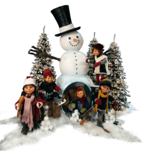 A group of children playing around a large snowman and lighted Christmas trees.