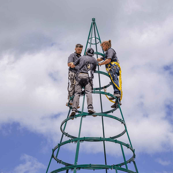 Three workers installing a commercial tower tree's steel frame.