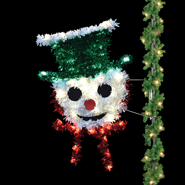 A pole mounted decoration of a snowman face wearing a green top hat, and a red scarf, made of colored garland and C9 LED lights.