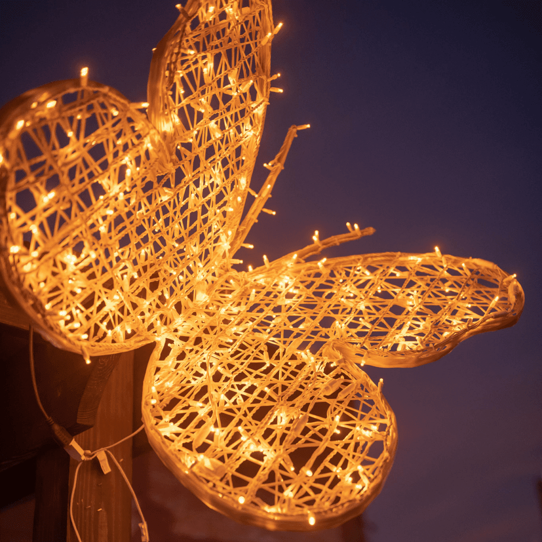 An image of a two dimensional yellow butterfly, made of fiberglass strings and yellow LED lights.
