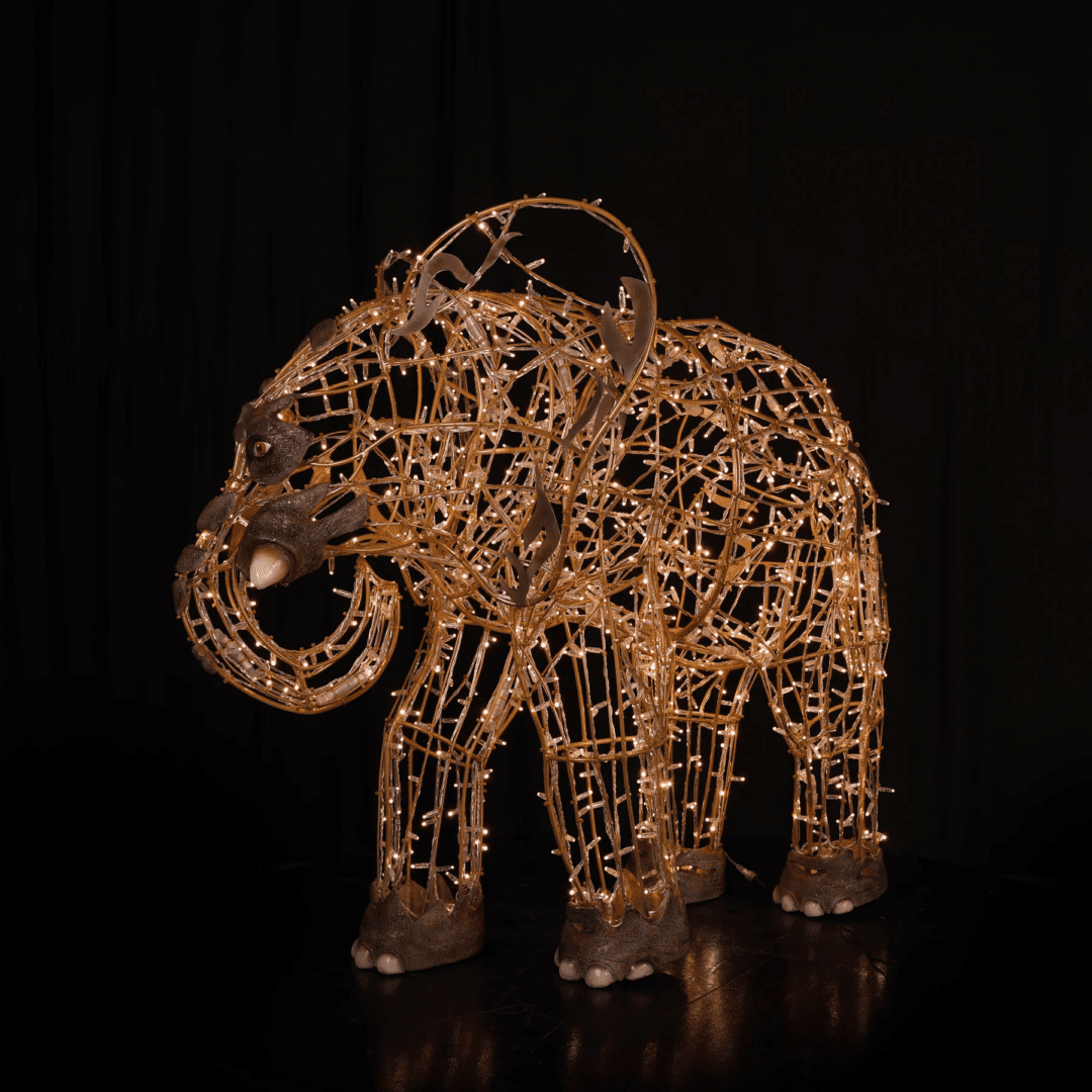 An image of a small elephant made of a wire frame, warm white mini LED Christmas lights, and fiberglass accents.