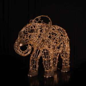 An image of a small elephant made of a wire frame, warm white mini LED Christmas lights, and fiberglass accents.