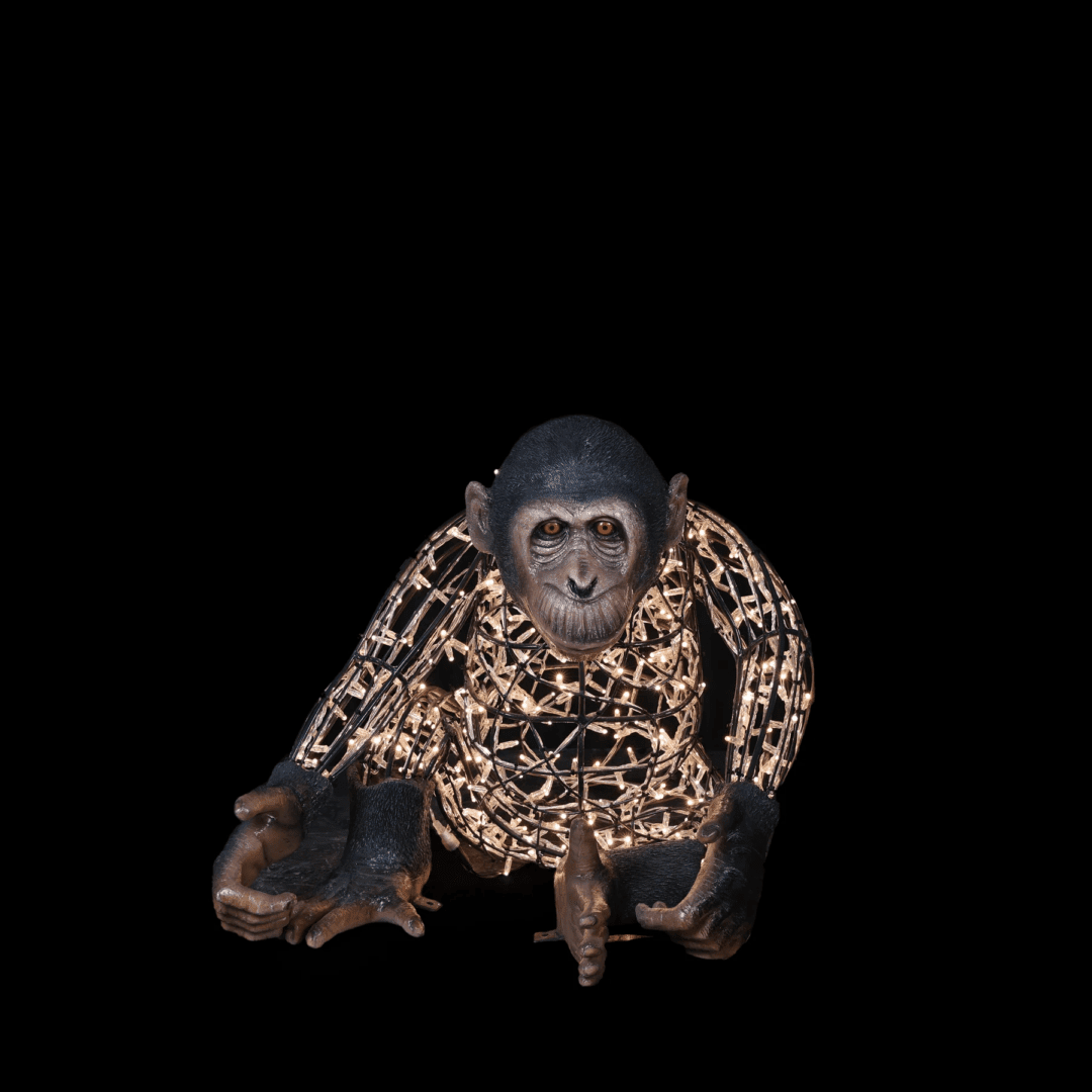 An image of a large 3d illuminated monkey, made of a wire frame, warm white mini LED Christmas lights, and fiberglass accents.