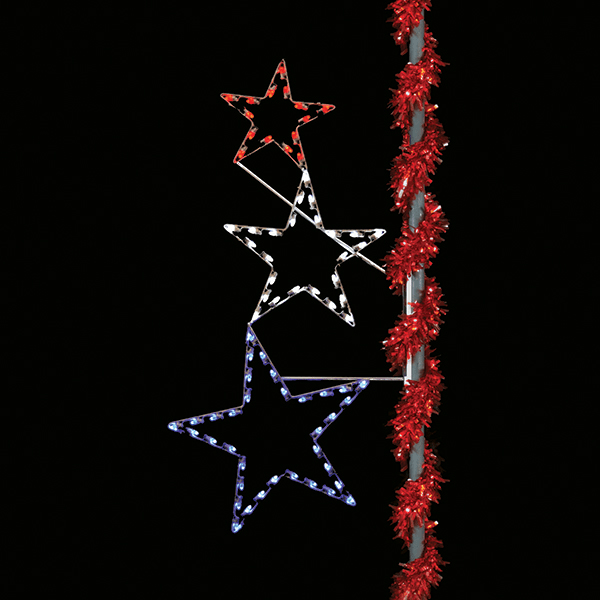 An image of three different sized stars stacked on top of each other. The stars are colored (from top to bottom) red, white, and blue. The stars are mounted on a silver pole decorated with red tinsel garland.