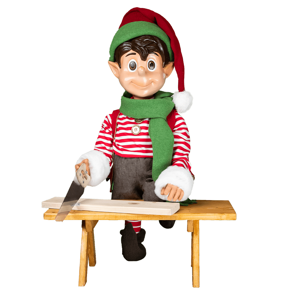 An image of an elf wearing Christmas colored clothing, sawing a piece of wood on a wooden bench.