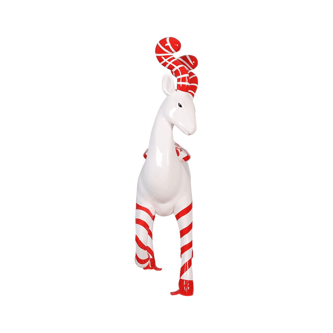 A statue of a white deer with red and white striped legs, and antlers. The deer also has two round peppermint candies on its back.