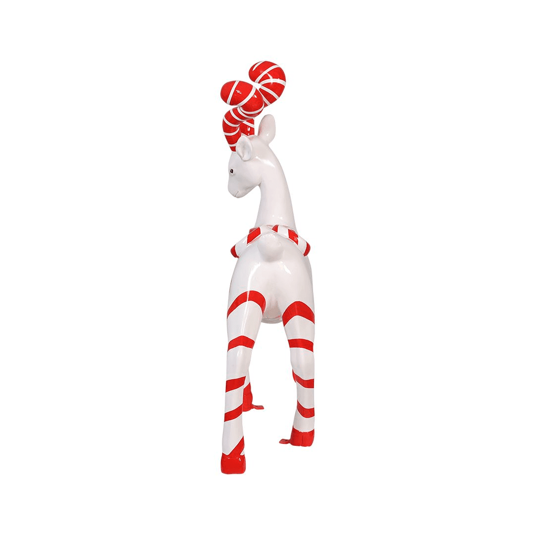 A statue of a white deer with red and white striped legs, and antlers. The deer also has two round peppermint candies on its back.