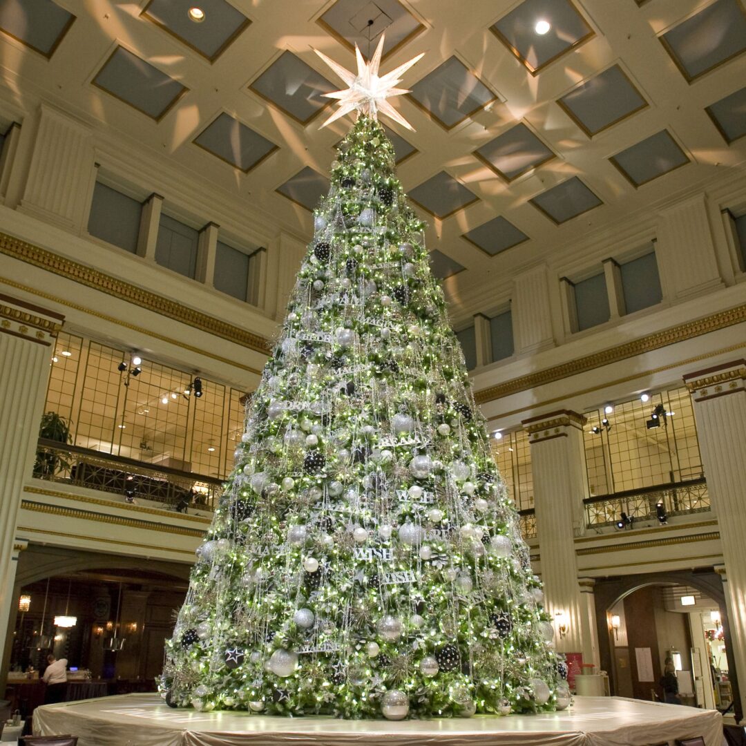 A large, outdoor artificial Everest Christmas tree, decorated with lights and ornaments.