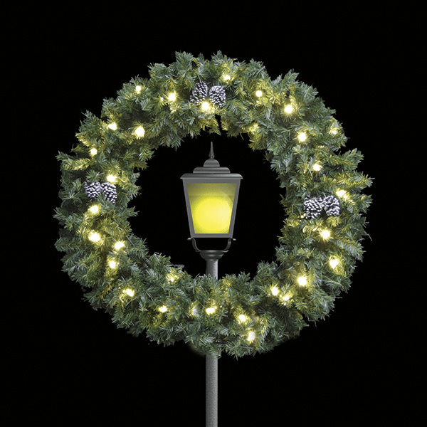 A large lighted Christmas wreath circling the top globe of a city lamp post.