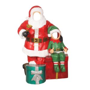 Santa Claus standing next to an elf, surrounded by presents.