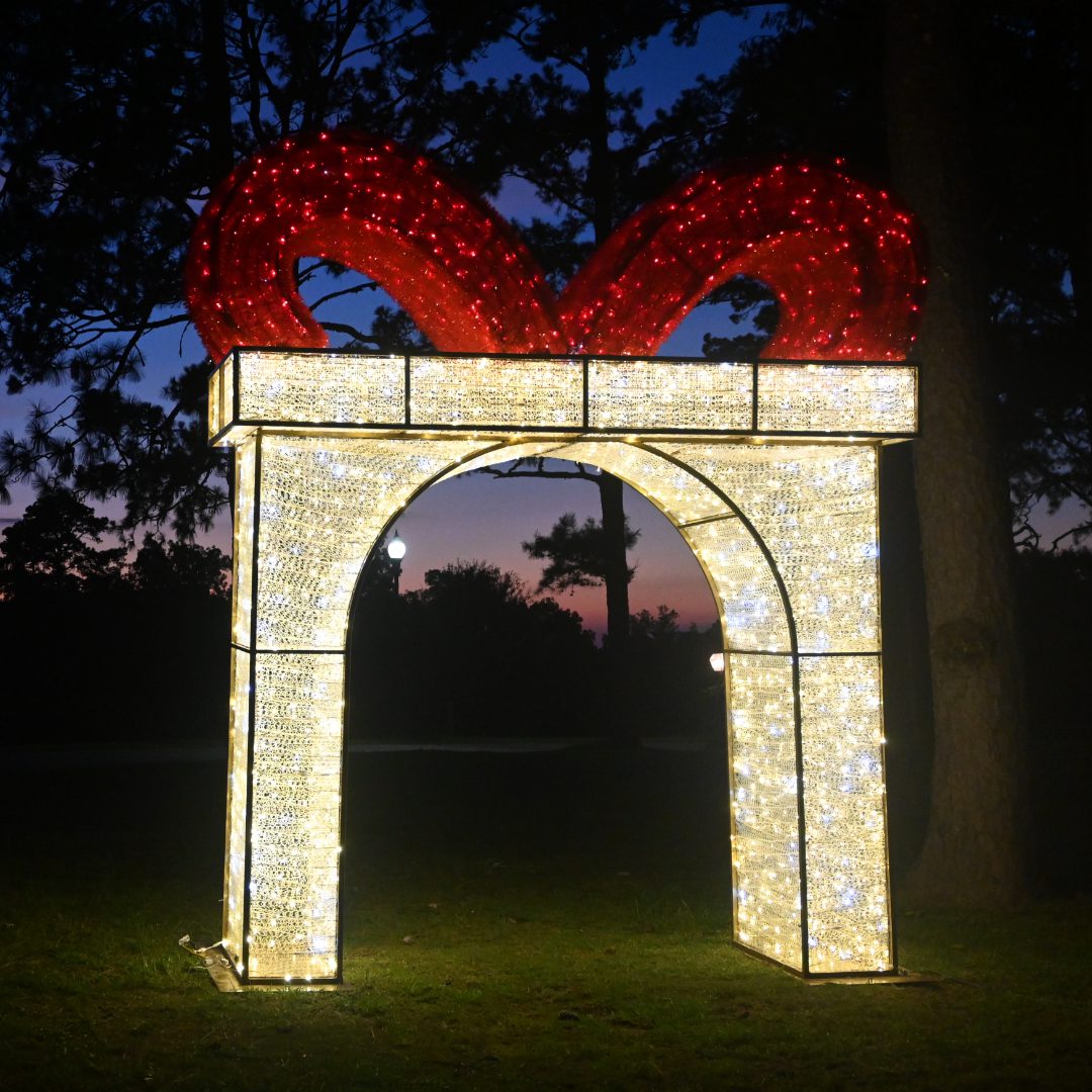 A large lighted archway in the shape of a Christmas gift box with a big red bow.