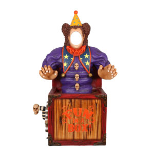 A scary clown in a purple shirt and a yellow hat, popping out of a crank wound box. The clown has the face cut out to allow for patrons to put their face into.