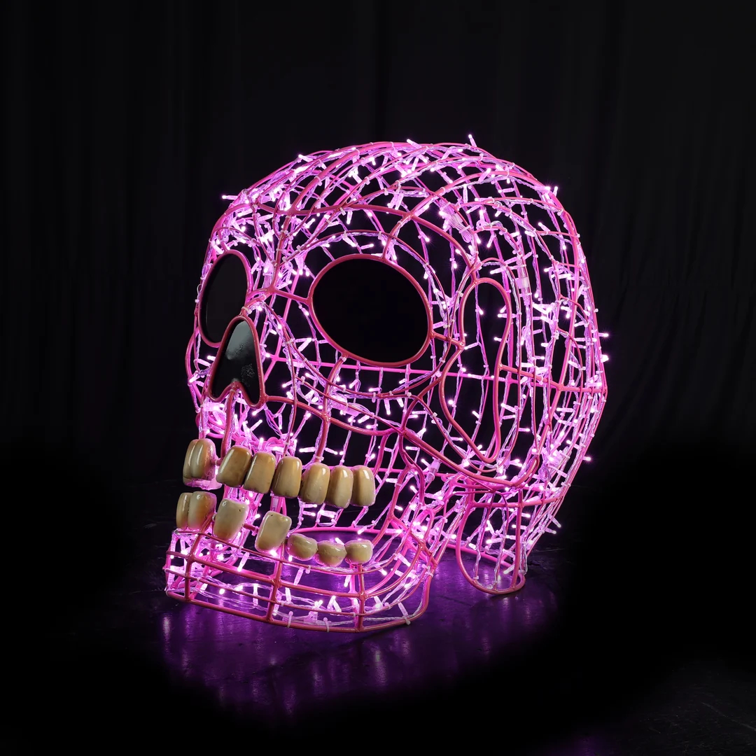 A Christmas light display of a 3D smiling human skull made from pink mini LED Christmas lights.